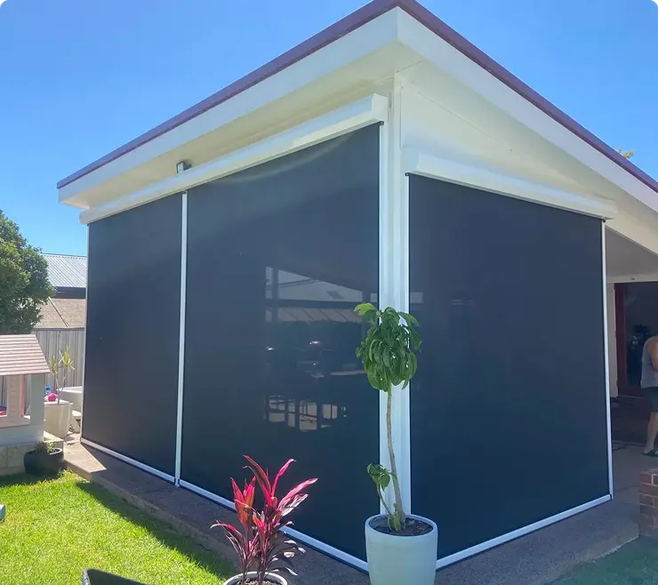 House with outdoor blinds and potted plants.
